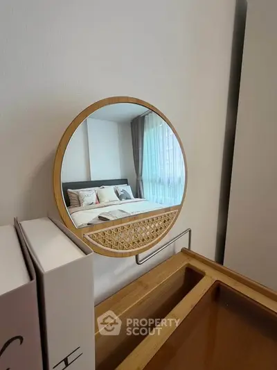 Stylish bedroom with modern decor and round mirror reflecting cozy bed setup.