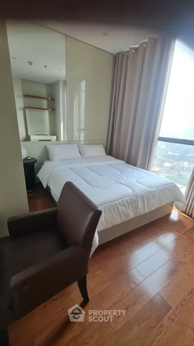 Cozy bedroom with large window offering city view and modern furnishings