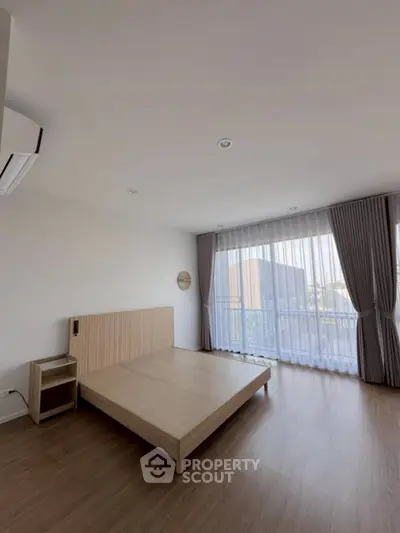 Spacious bedroom with large window and modern minimalist design