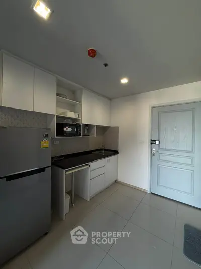 Modern kitchen with sleek cabinets and stainless steel fridge in a bright apartment.