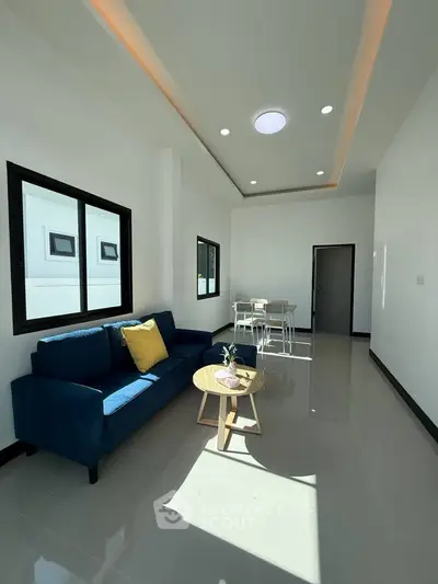 Modern living room with sleek design and natural light, featuring a blue sofa and stylish decor.
