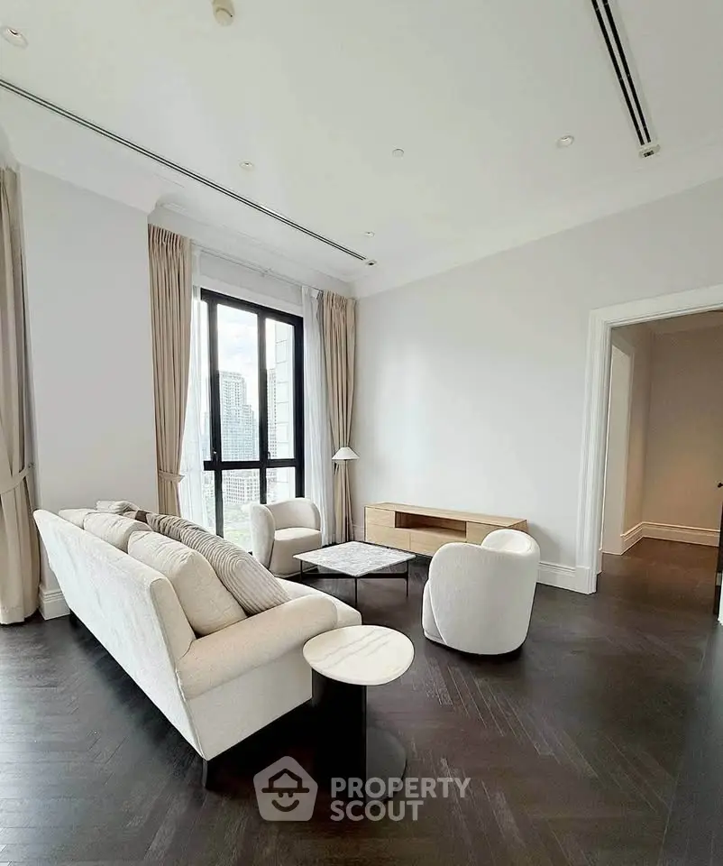 Elegant living room with modern furniture and city view, featuring high ceilings and natural light.