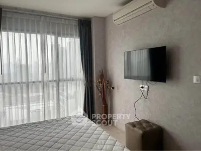 Modern bedroom with large window, wall-mounted TV, and air conditioning in a stylish apartment.