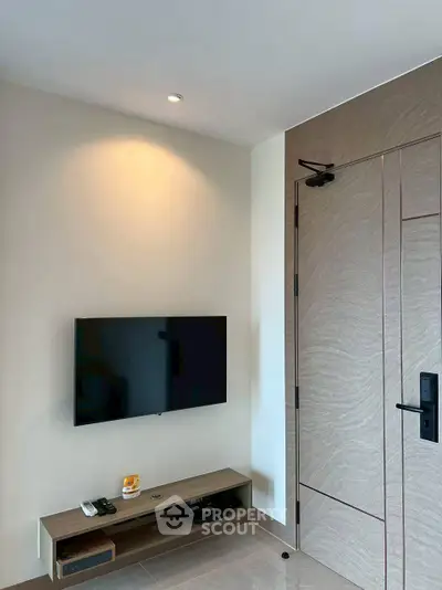Modern living room corner with wall-mounted TV and sleek wooden door
