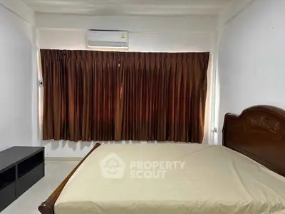 Cozy bedroom with air conditioning and large window with brown curtains.