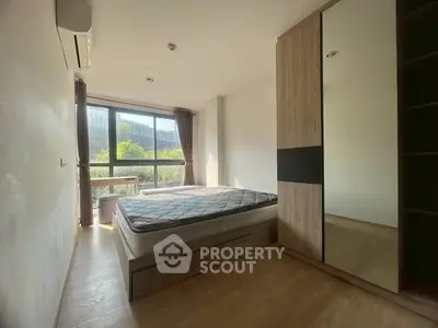 Spacious bedroom with large window and modern wardrobe, offering ample natural light and serene ambiance.