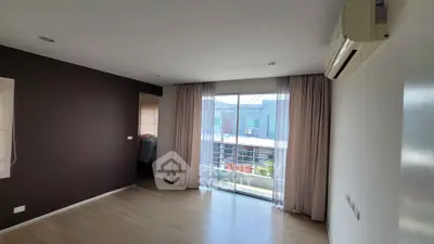 Spacious living room with large window and air conditioning, offering a bright and airy atmosphere.