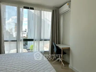 Bright bedroom with large windows, modern furnishings, and city view, perfect for urban living.
