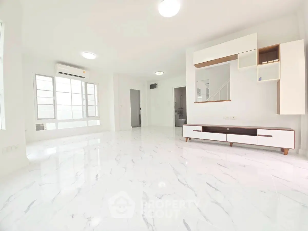 Spacious modern living room with sleek white marble flooring and minimalist furniture.