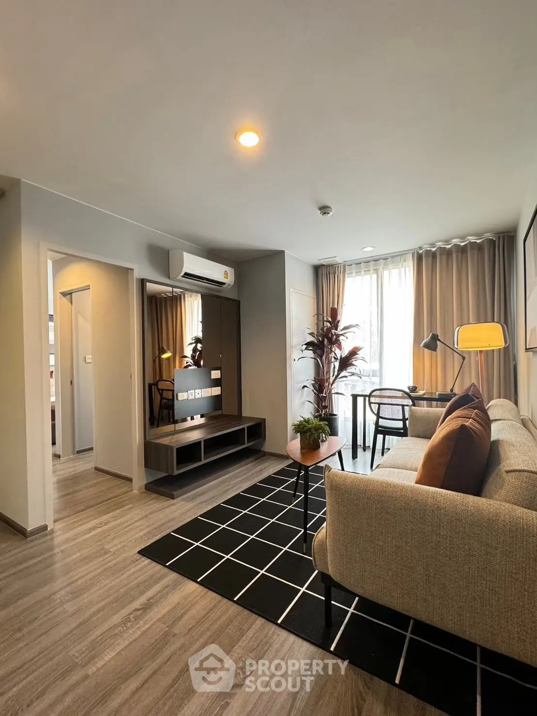 Modern living room with stylish decor, featuring a cozy sofa, sleek TV stand, and natural light from large windows.