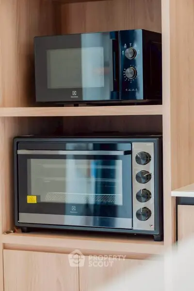 Modern kitchen appliances in sleek wooden cabinetry, showcasing a stylish microwave and oven for contemporary living.
