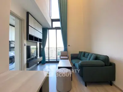 Modern living room with high ceiling and balcony access in stylish apartment.