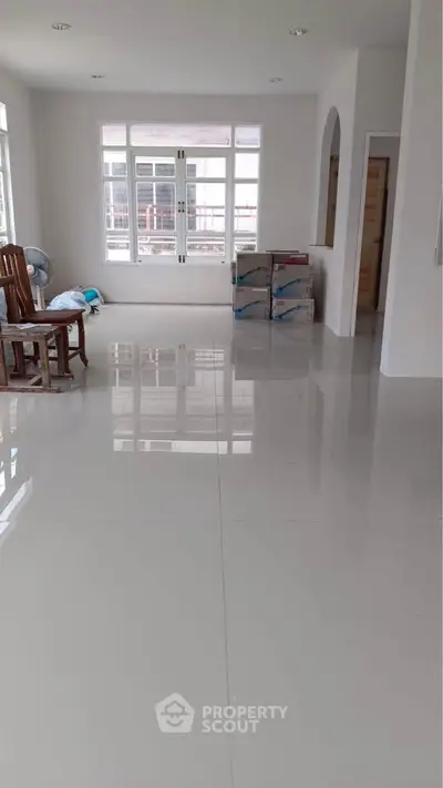 Spacious empty room with glossy tiled floors and large windows for natural light.