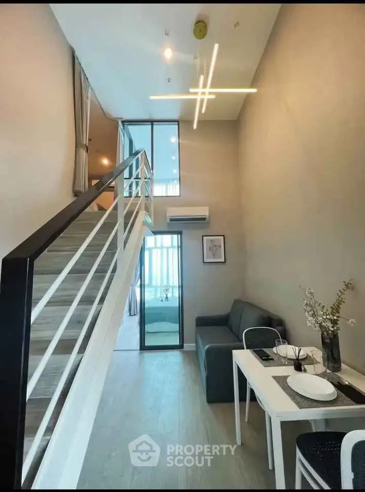 Modern loft apartment with stylish interior and high ceiling, featuring a cozy living area and sleek staircase.