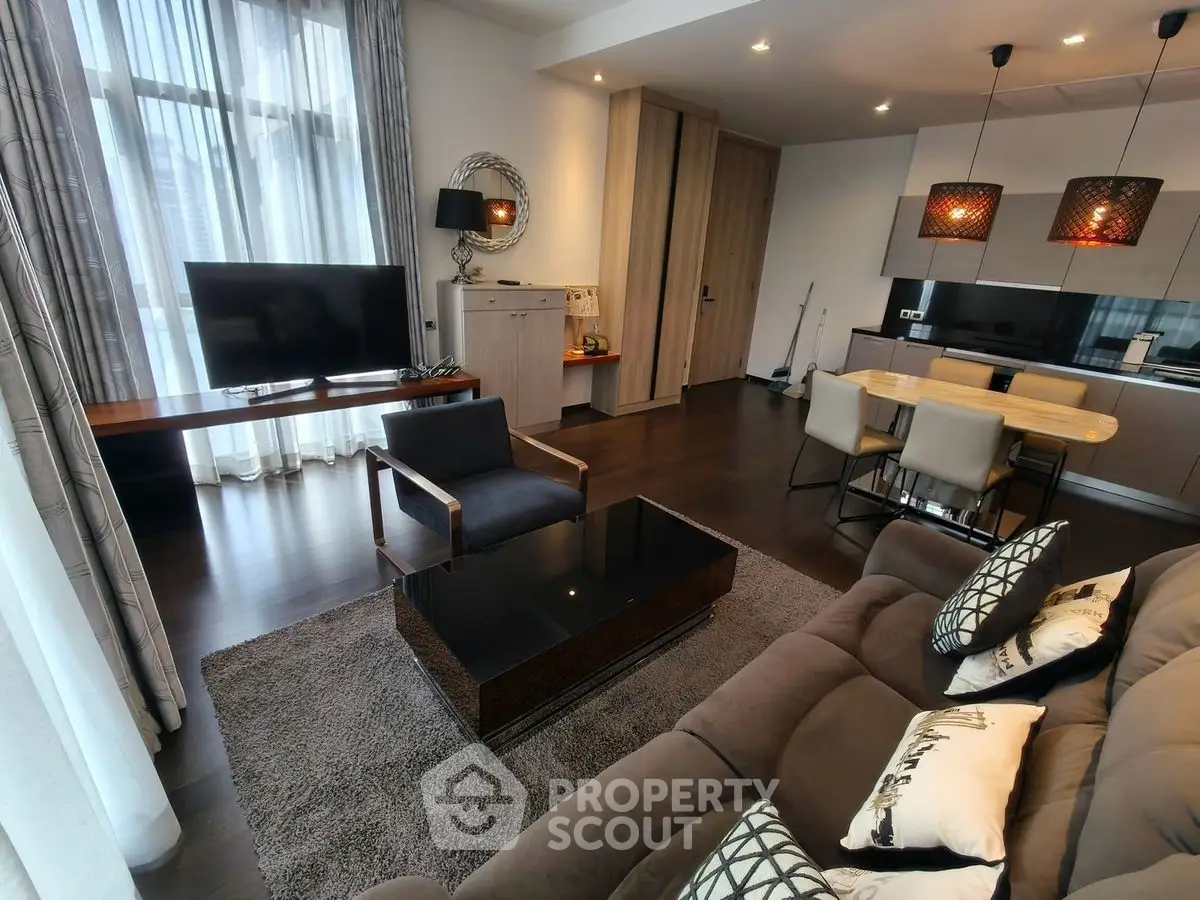 Modern living room with stylish decor and open kitchen layout, featuring sleek furniture and natural light.