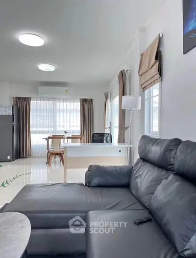 Spacious modern living room with sleek black leather sofa and natural light