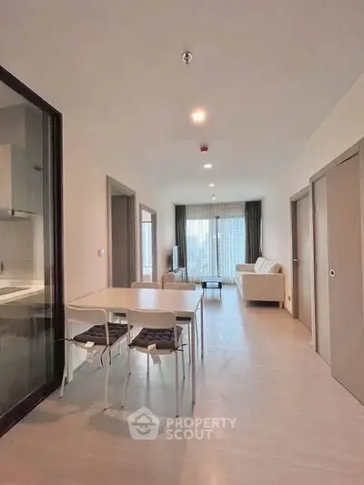 Spacious modern living room with dining area and large windows in a contemporary apartment.