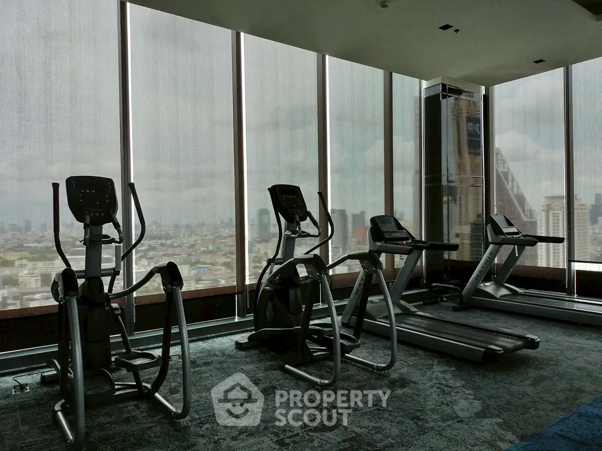 Modern gym with city view in high-rise building, featuring state-of-the-art exercise equipment.