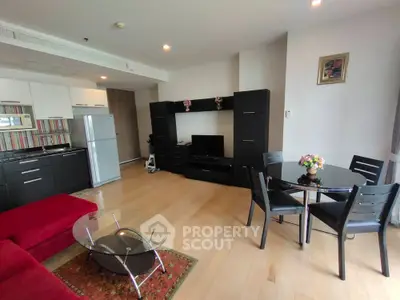Modern living room with open kitchen, stylish furniture, and cozy dining area.