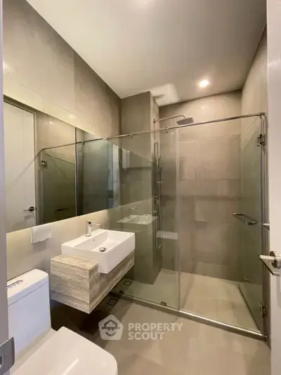 Modern bathroom with glass shower enclosure and sleek fixtures in a contemporary apartment.