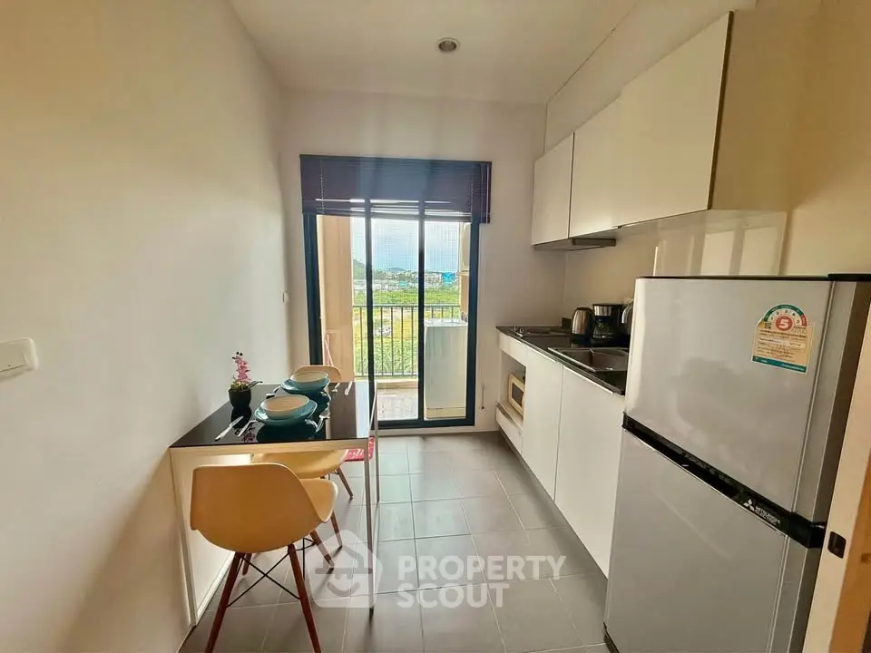 Modern kitchen with balcony view, sleek cabinetry, and dining area in a stylish apartment.