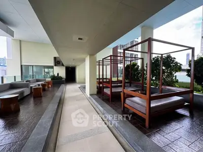 Modern outdoor lounge area with stylish seating and greenery in a luxury building.