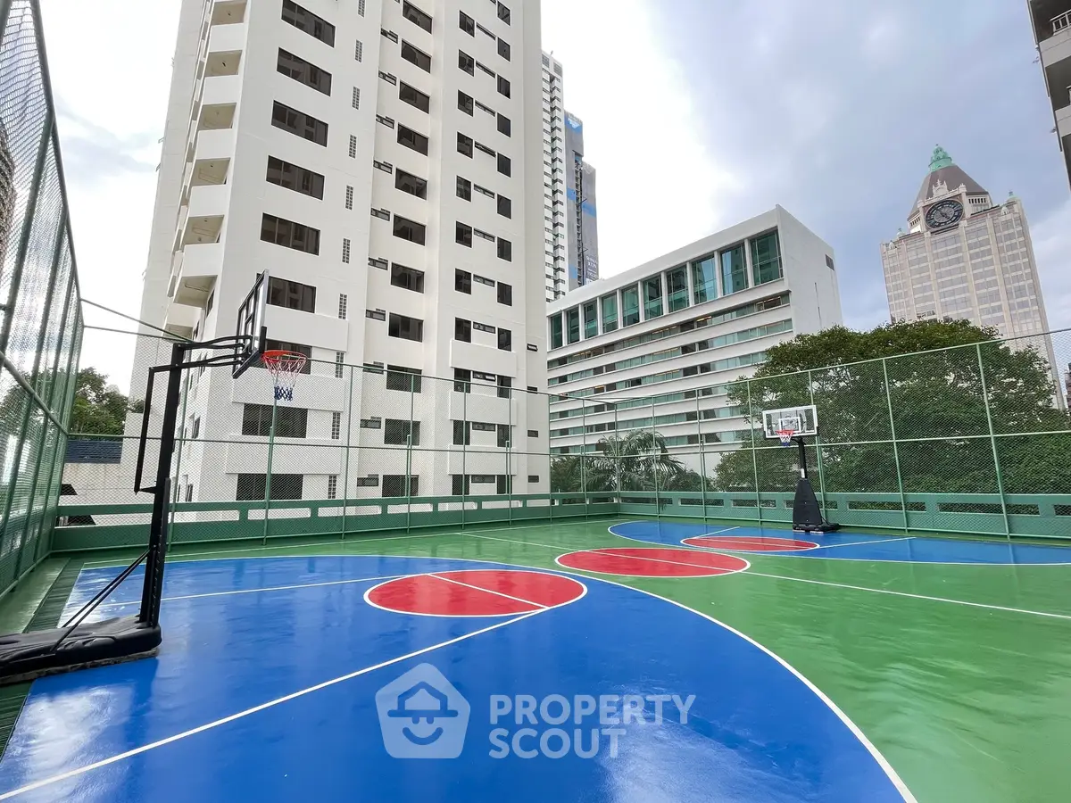 Modern residential building with vibrant outdoor basketball court in urban setting.