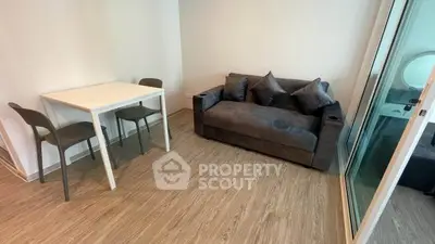 Modern living room with sleek sofa and dining table, featuring stylish wooden flooring.