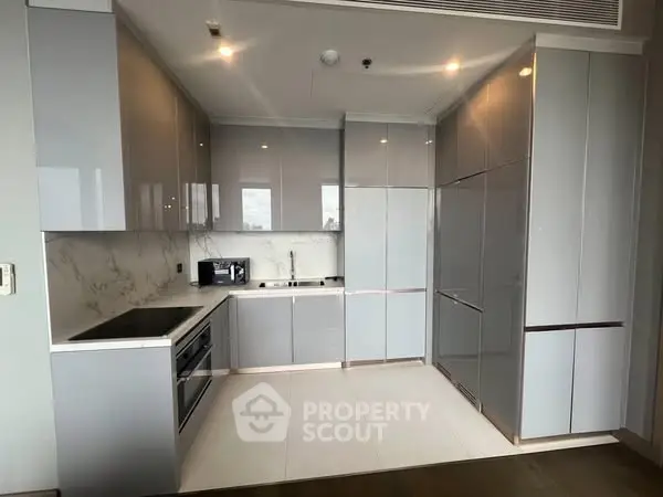 Modern kitchen with sleek cabinetry and marble backsplash in luxury apartment.