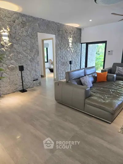 Luxurious living room with stone accent wall and modern leather sofa, offering a spacious and elegant ambiance.