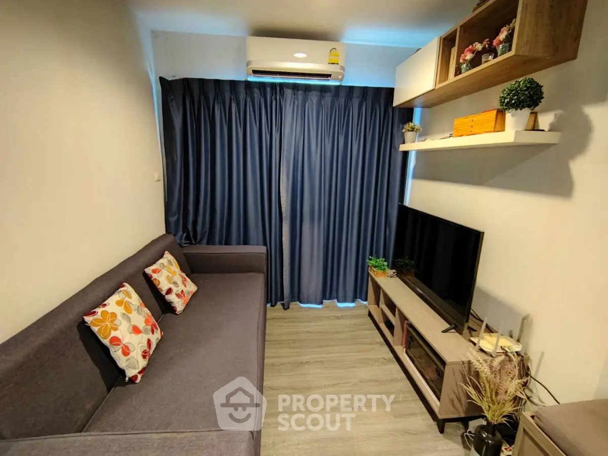 Cozy living room with modern decor, featuring a comfortable sofa, flat-screen TV, and stylish shelving.