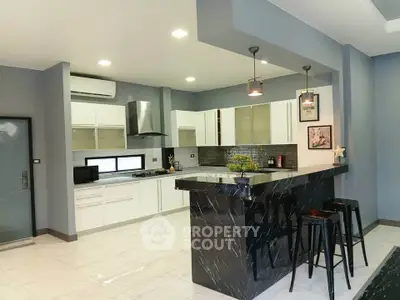 Modern kitchen with sleek black marble island and white cabinetry in open layout