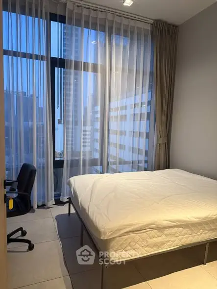 Modern bedroom with large windows and city view, featuring a comfortable bed and sleek design.