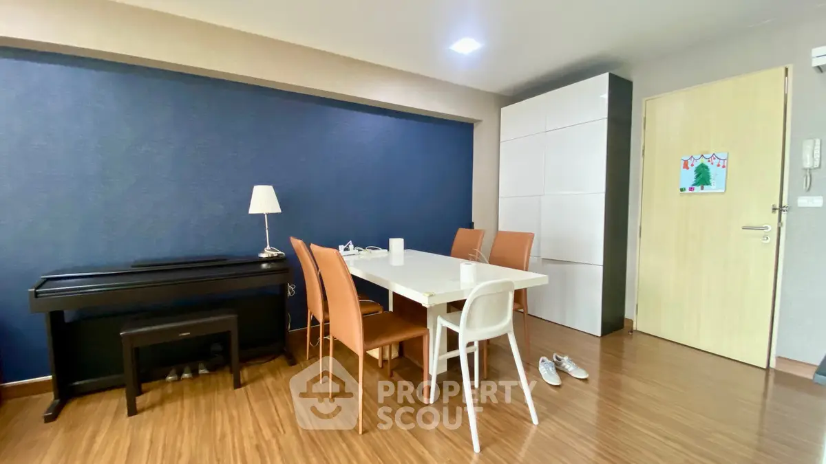 Modern dining area with sleek table, chairs, and piano in stylish apartment.