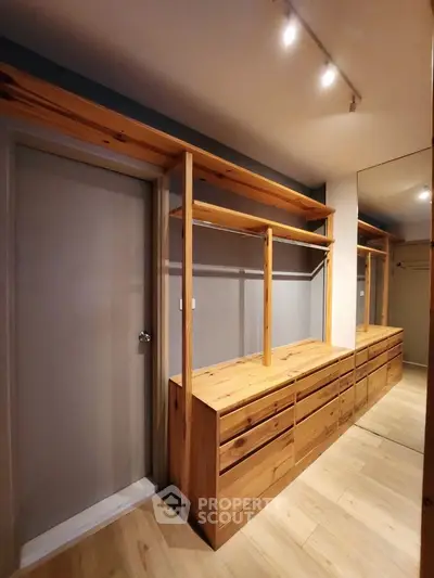 Spacious walk-in closet with wooden cabinetry and modern lighting