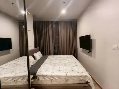 Modern bedroom with cozy bedding and wall-mounted TV in a stylish apartment.
