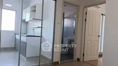 Modern apartment interior with compact kitchen and bathroom view.