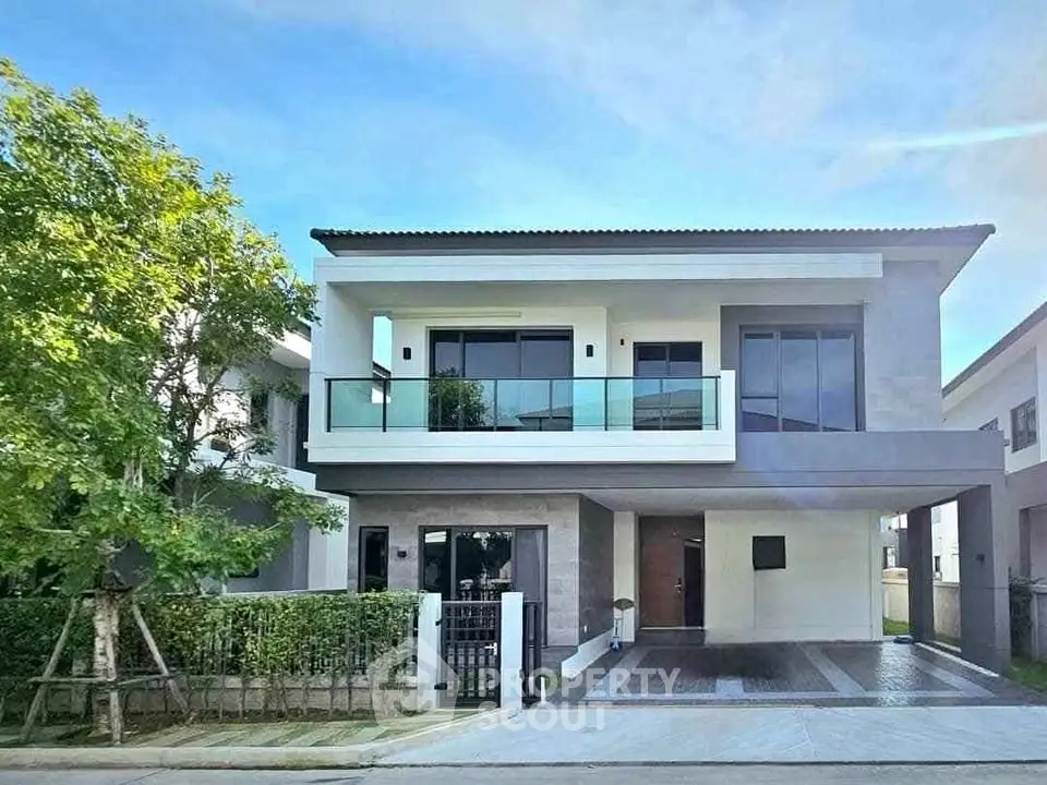 Modern two-story house with glass balcony and sleek exterior design.