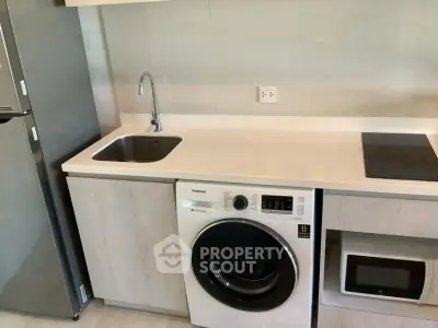 Modern kitchen with integrated appliances including washing machine and microwave.