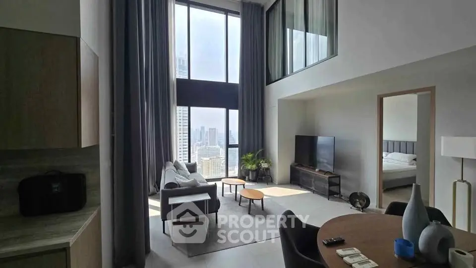 Spacious modern living room with high ceilings and city view, featuring stylish furniture and natural light.