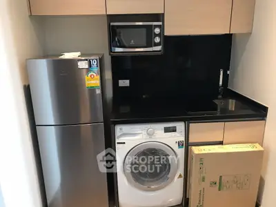 Modern compact kitchen with appliances including fridge, microwave, and washing machine.