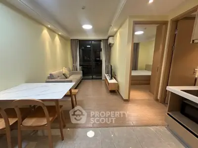 Modern open-plan living room with cozy seating and dining area, featuring elegant lighting and wooden flooring.