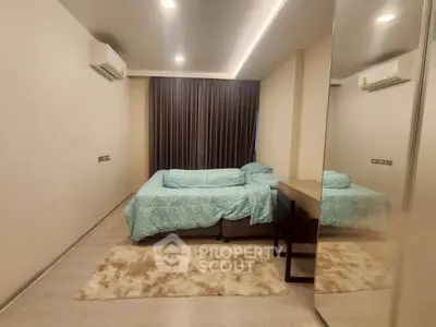Spacious bedroom with modern decor and large mirror, featuring cozy bedding and ambient lighting.
