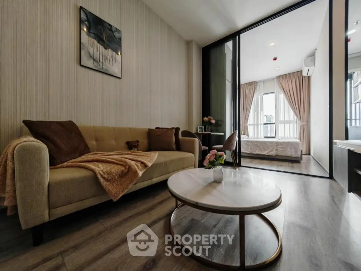 Modern living room with cozy sofa and stylish decor leading to a bright bedroom with balcony view.