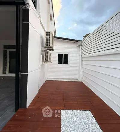 Modern exterior patio with wooden deck and white privacy fence