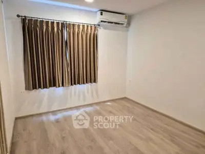 Spacious empty room with wooden flooring and air conditioning, ideal for customization.