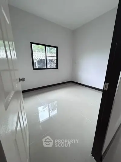 Spacious empty room with glossy tiled floor and window view, perfect for customization.