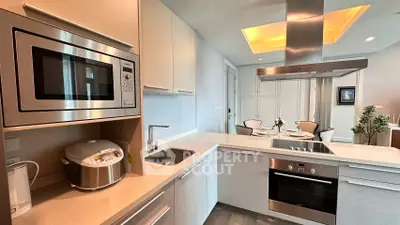Modern kitchen with sleek appliances and elegant dining area, featuring a built-in oven and microwave.