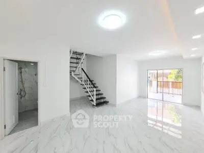 Spacious modern living room with marble flooring and staircase, abundant natural light, and balcony access.