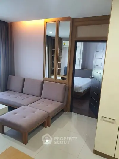 Modern living room with cozy sofa and view into a stylish bedroom